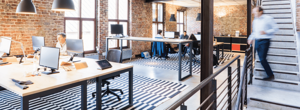 office scene with multiple workspaces and people at their desks