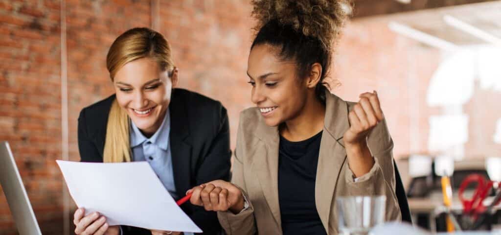 two workers in an office looking at paper together and talking
