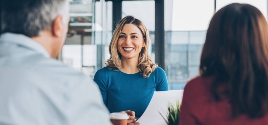 smiling woman talking to two others in office