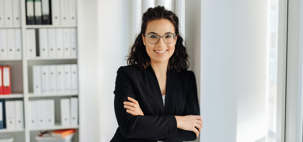 young gen z worker standing in white office space smiling at camera